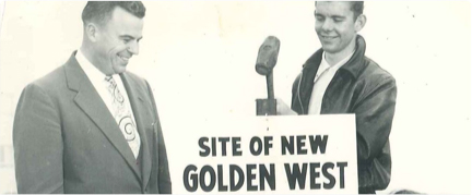 Two men with a sign that says "Site of New Golden West." One man is holding a hammer and the other is smiling.