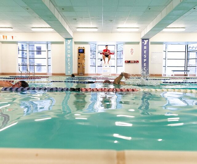 Swimmer in the pool as a lifeguard watches on.