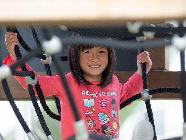 Young girl playing on children's outdoor play structure
