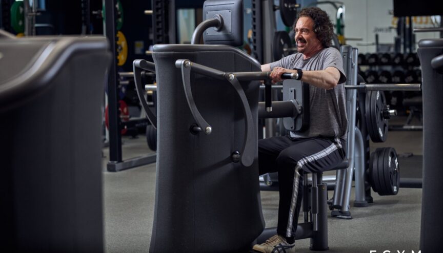 Man sitting in front of a weight resistance machine looking at a screen
