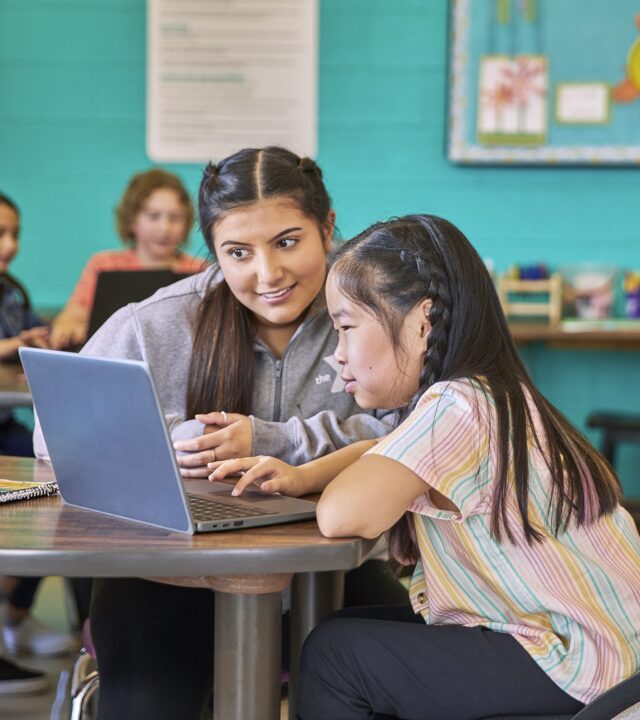 Adult and youth looking at a laptop screen.
