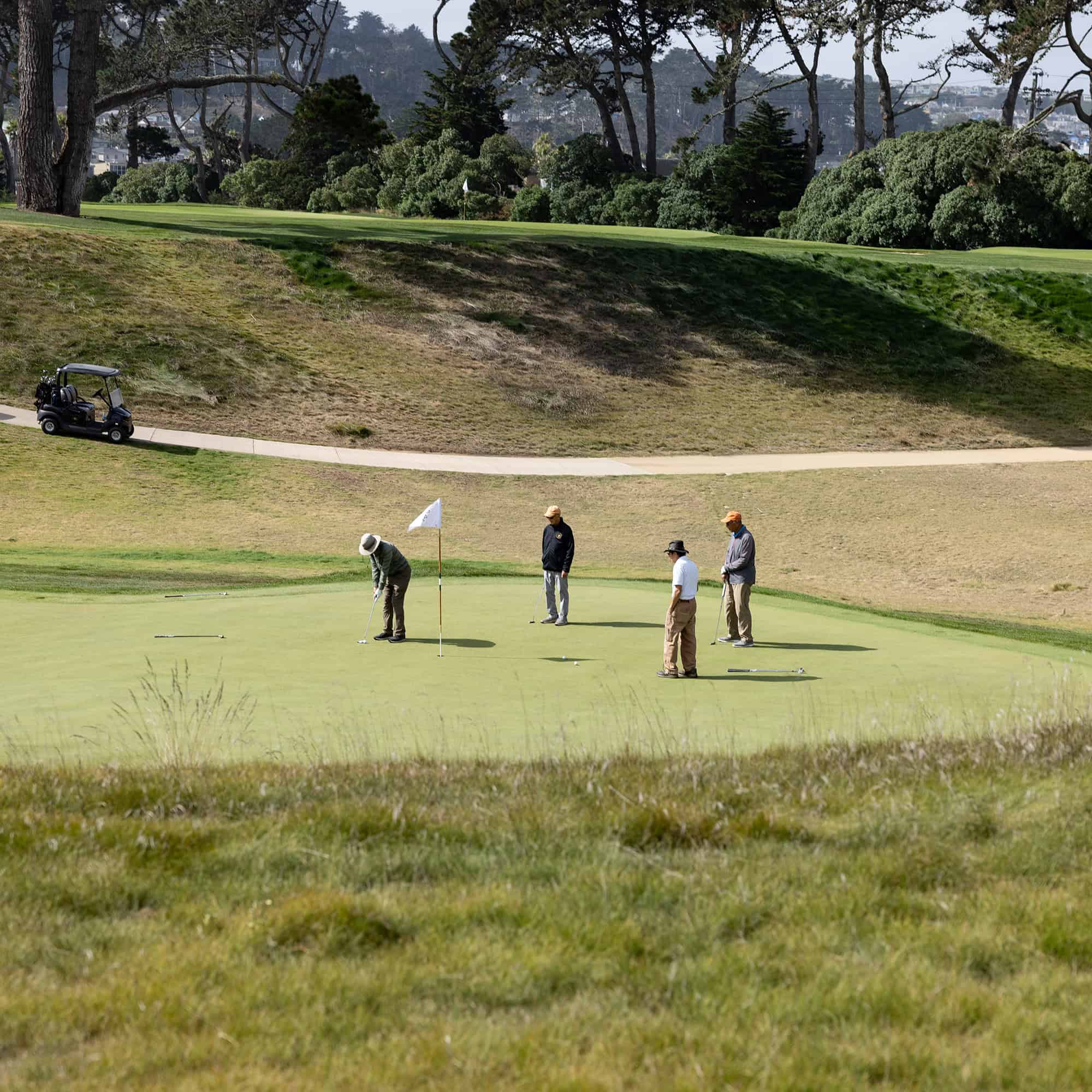 Four golfers standing on a putting green.