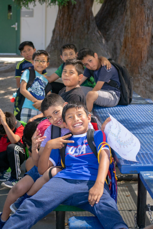 Marin YMCA - A group of boys in backpacks poses for the photo. One boy is presenting the peace sign with his fingers.