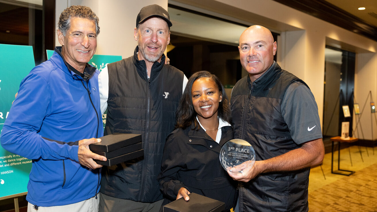 Three adult males and one adult female holding awards from a golf tournament.
