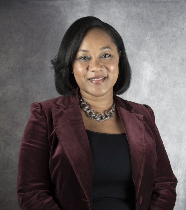 A woman in a maroon blazer and black shirt.