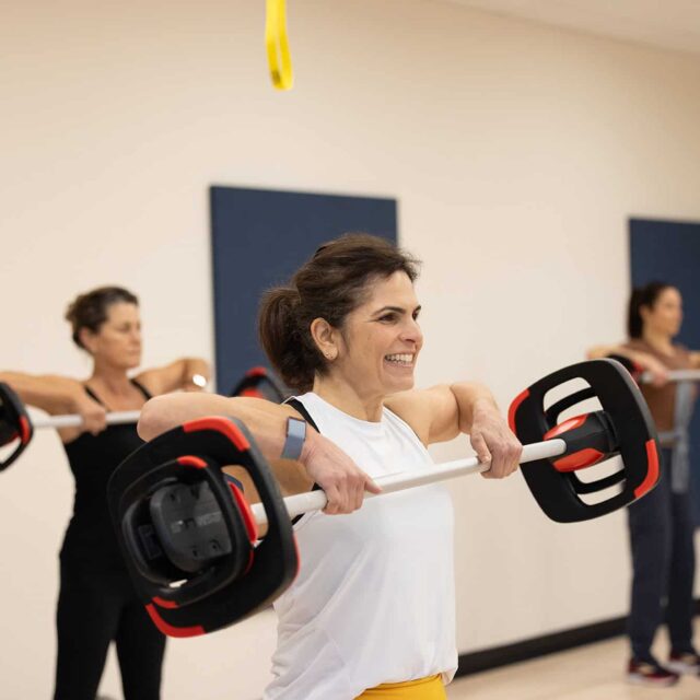 A woman is lifting a barbell in a gym.