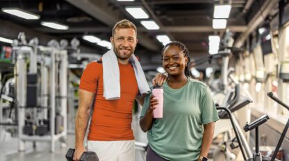 Two cheerful individuals in a gym setting display their active lifestyles and camaraderie, promoting health and fitness awareness.