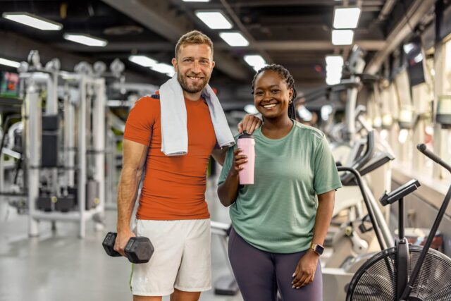 Two cheerful individuals in a gym setting display their active lifestyles and camaraderie, promoting health and fitness awareness.