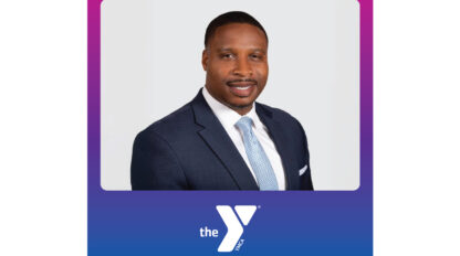 A man in a dark suit and light blue tie poses for a professional portrait against a light background, framed by a purple and blue border with the YMCA of Greater San Francisco logo at the bottom, reflecting their Vision 2030 community impact.