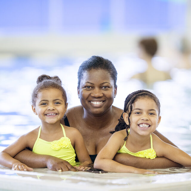 Adult female with two female youth in a swimming pool.