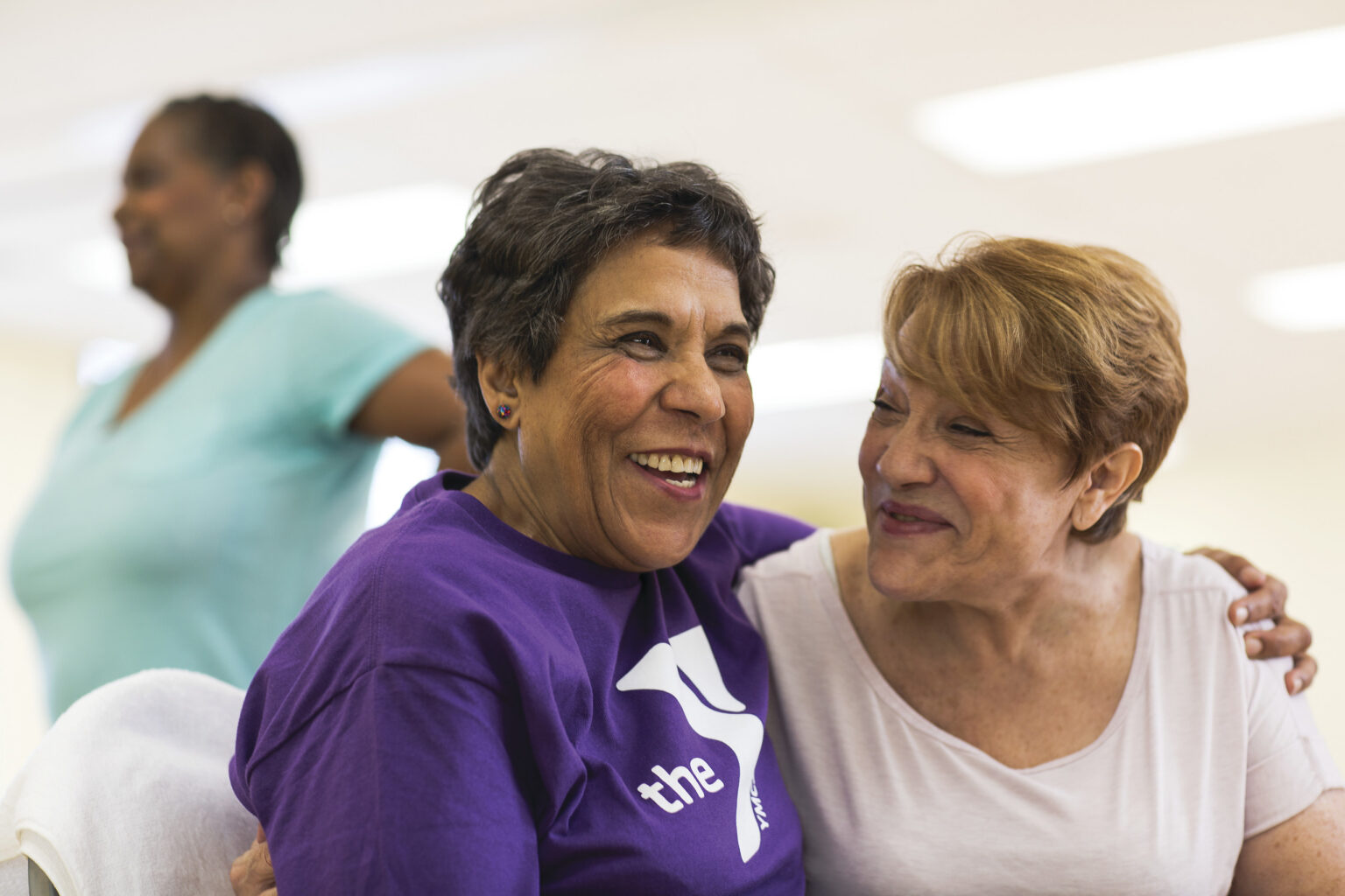 This image shows two women embracing before a group exercise class