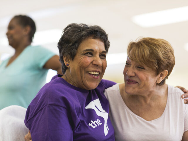 This image shows two women embracing before a group exercise class