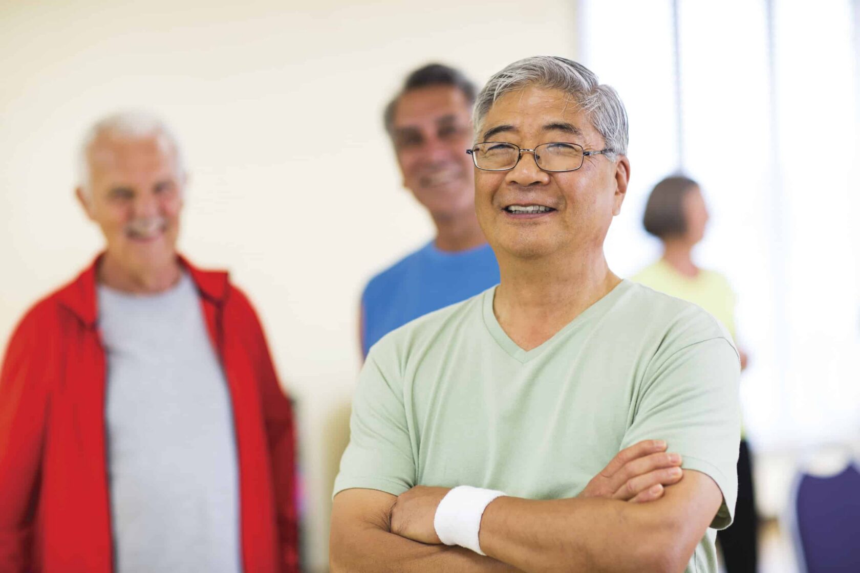 Diverse trio of active older adult men waiting for a group class to begin.