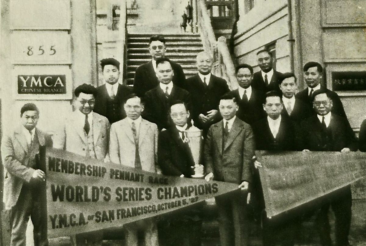 A group of men in suits pose outside a building, holding a trophy and a banner that reads “World’s Series Champions YMCA San Francisco, October 8, 1935,” capturing a proud moment in time that echoes the legacy celebrated in Five YMCA Anniversaries Tell Story of San Francisco’s Community History.
