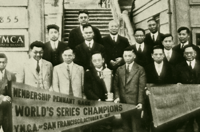 A group of men in suits pose on building steps holding a trophy and a banner reading “World’s Series Champions, YMCA of San Francisco, October 8, 1913,” offering a historic glimpse that ties into the Five YMCA Anniversaries Tell Story of San Francisco’s Community History.