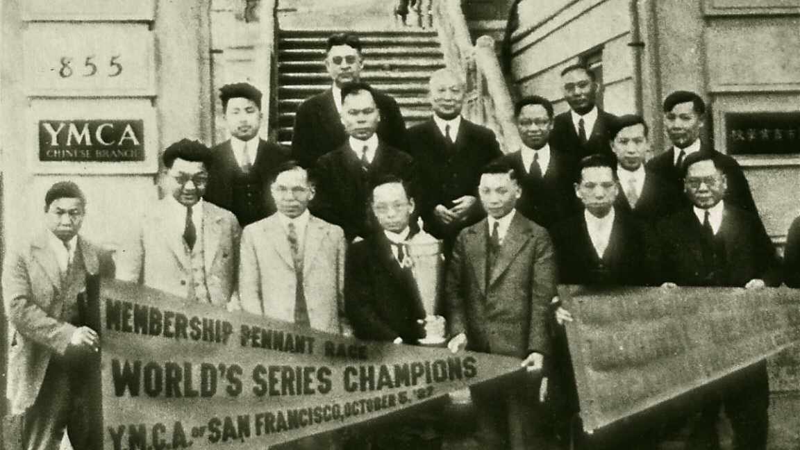 A group of men in suits pose on building steps holding a trophy and a banner reading “World’s Series Champions, YMCA of San Francisco, October 8, 1913,” offering a historic glimpse that ties into the Five YMCA Anniversaries Tell Story of San Francisco’s Community History.
