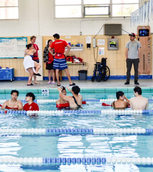 Lifeguards in training practice water rescue techniques in an indoor pool for the YMCA San Francisco annual report.